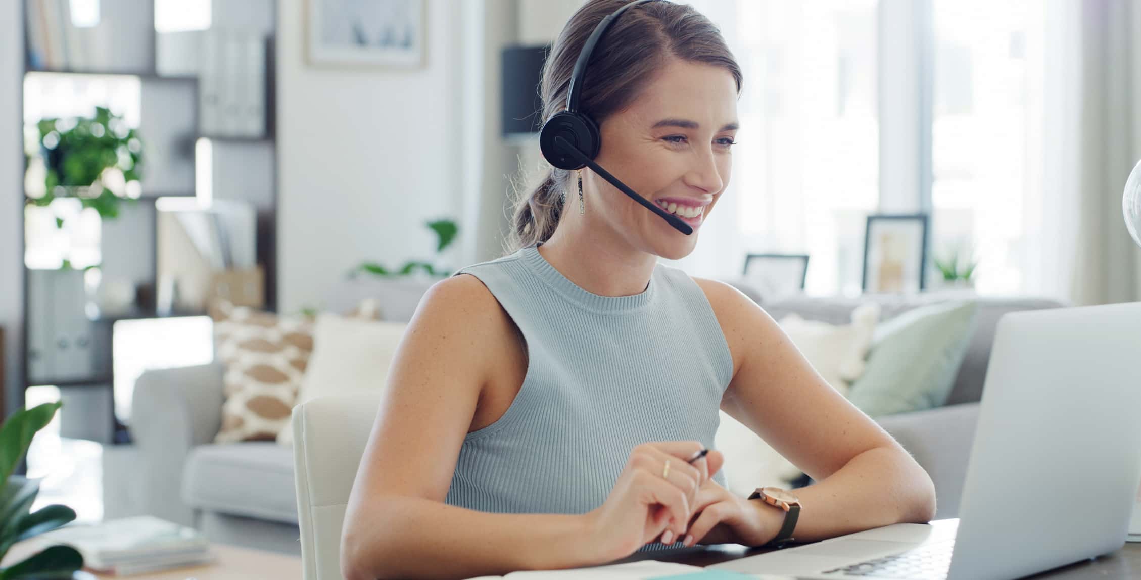 Headset, laptop and support with freelance woman in living room of home for customer service. Communication, computer and smile of remote work employee