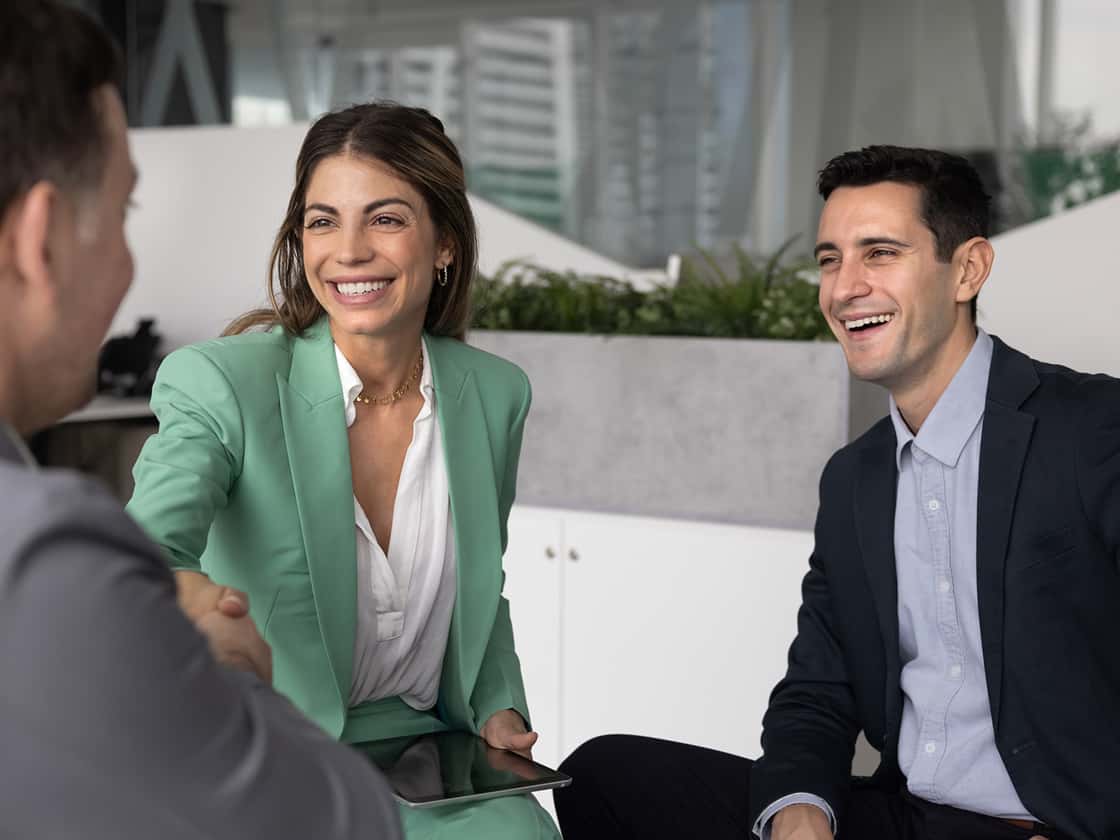 Smiling Hispanic business woman shaking hands with man